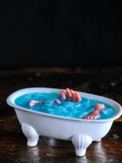 Blue curacao cocktail recipein white bathtub cocktail glass, body parts in cocktail