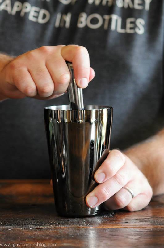 Muddling ingredients in a cocktail shaker