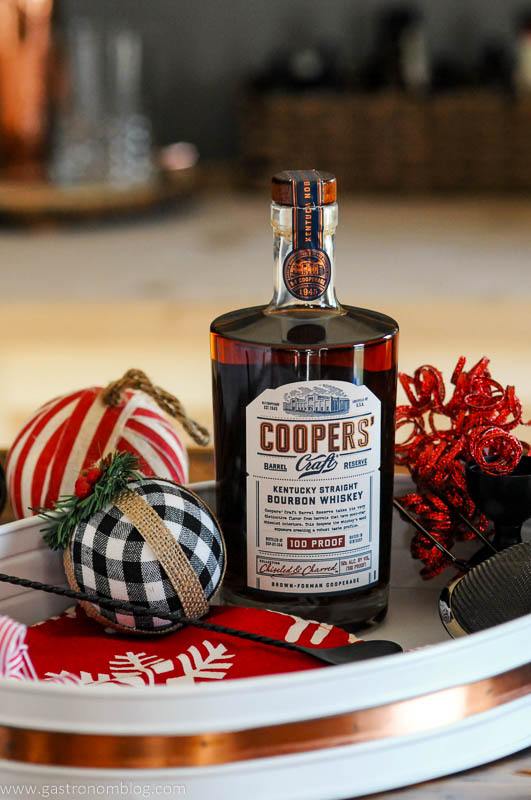 Coopers' Craft Bourbon bottle on white tray with Christmas ornaments around