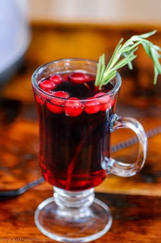 Red cocktail in mug with cranberries and rosemary