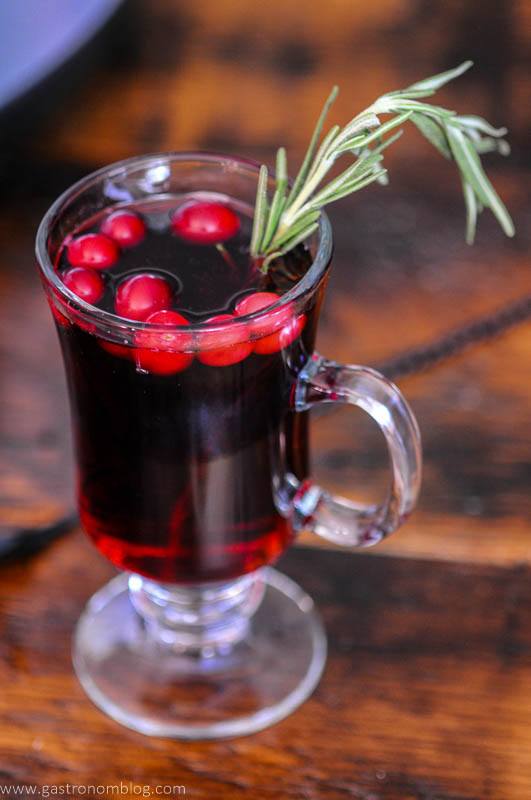 Red cocktail in mug with cranberries and rosemary