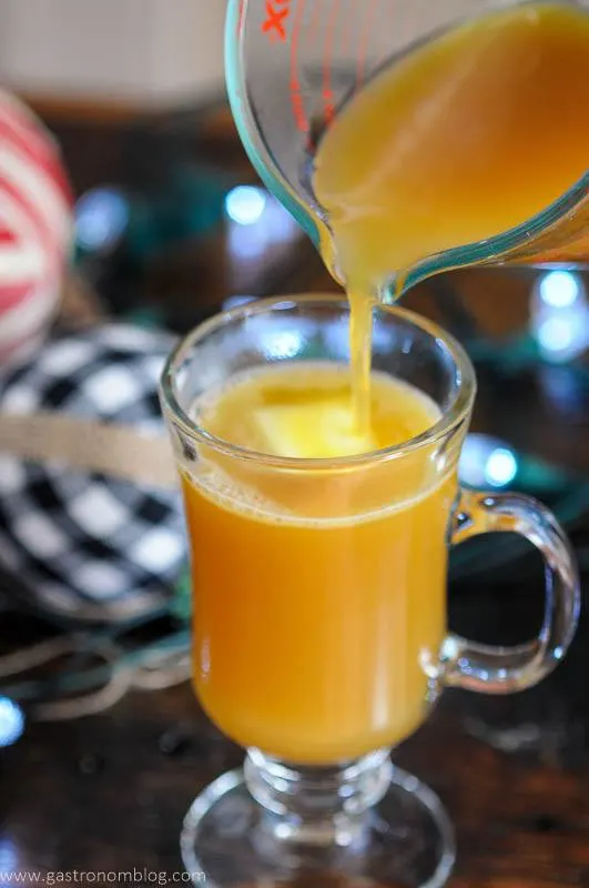 Pouring cider into glass with butter