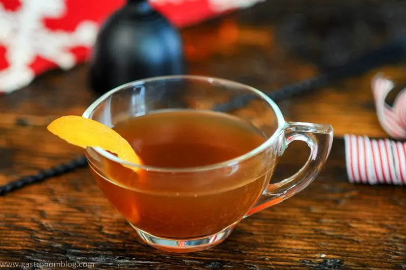 tan cocktail in a teacup, orange zest