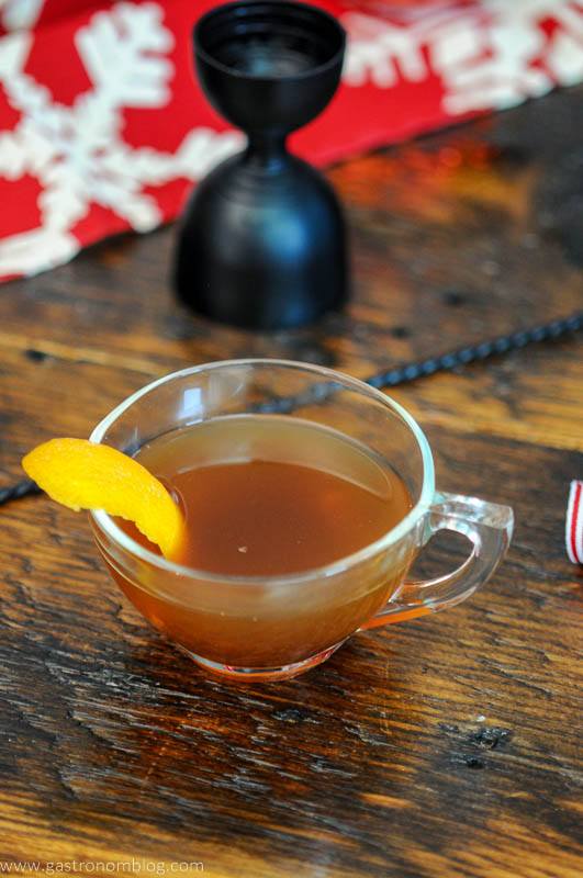 tan cocktail in a teacup, orange zest