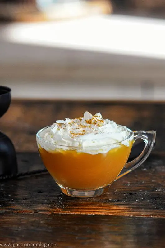 Bourbon Apple Cider Cocktail, in tea cup, topped with whipped cream and cinnamon