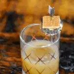 Gold etched glass with cocktail, tiny s'more on garnish pick