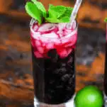 Blueberry Non Alcoholic Mojito, red cocktail in tall glass, mint and silver dot straw, limes