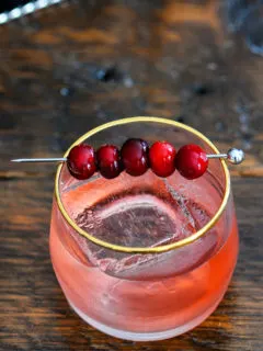 Top shot of cranberry mezcal cocktail with cranberries on a cocktail pick