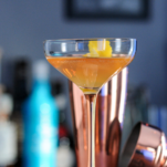 Cocktail in coupe with copper barware behind