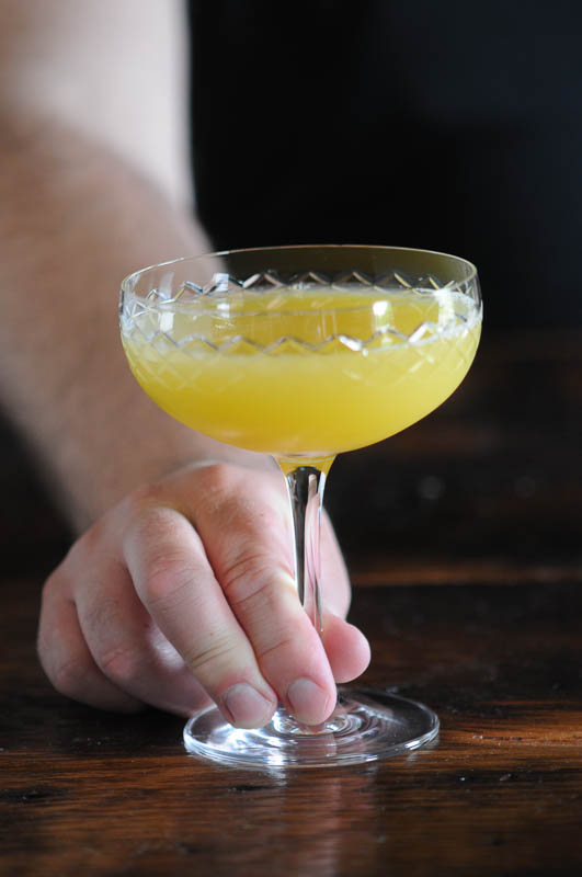 Golden Doublet cocktail in cocktail coupe, held in hand