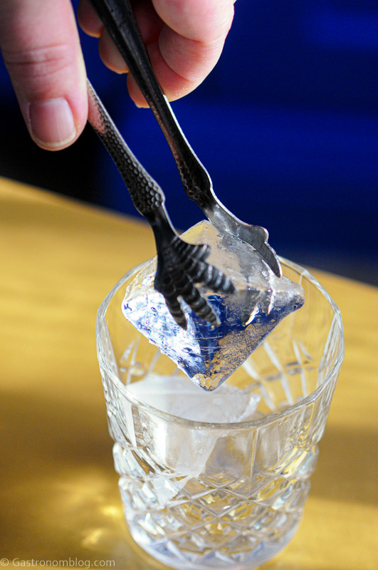 ice being placed in glass with ice tongs