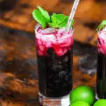 Blueberry Non Alcoholic Mojito, red cocktails in tall glass with mint, silver dot straw, limes
