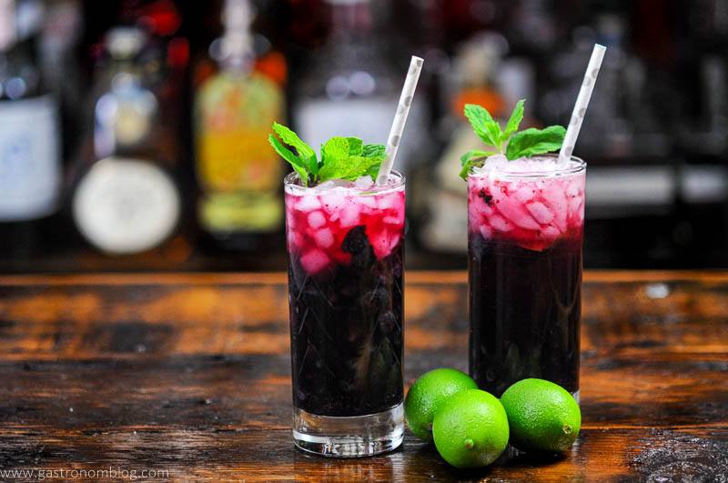 Blueberry Non Alcoholic Mojito, red cocktails in tall glasses, mint and silver dotted straws, limes