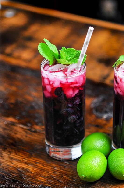 Blueberry Non Alcoholic Mojito, dark red cocktail in tall glass with mint and straw, limes next to glass