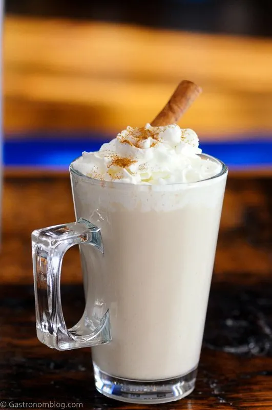 Coffee cocktail in glass mug with whipped cream and cinnamon stick