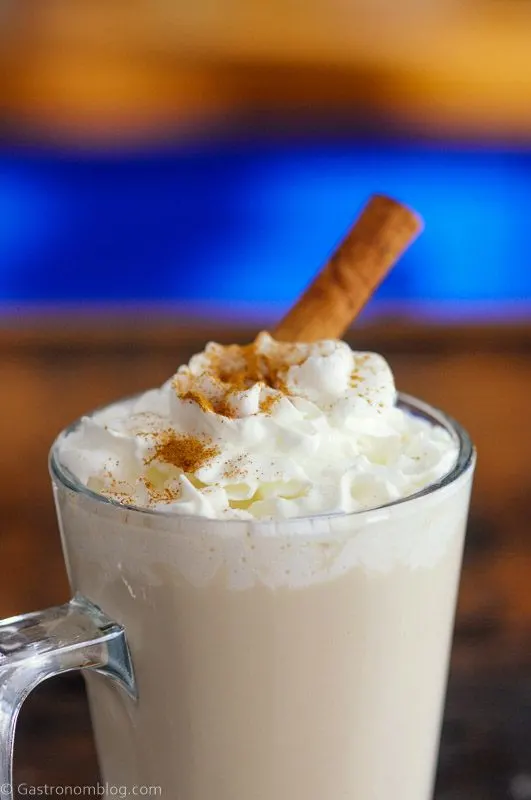 Coffee cocktail in glass mug with whipped cream and cinnamon stick