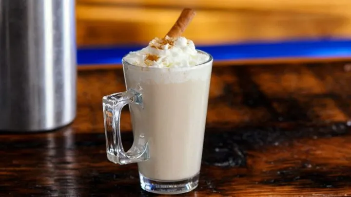 Coffee cocktail in glass mug with whipped cream and cinnamon stick