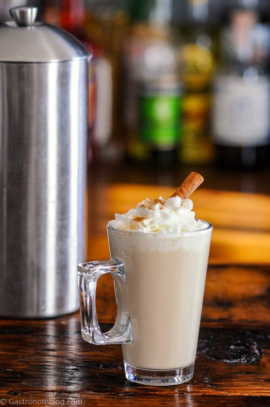 Coffee cocktail in glass mug with whipped cream and cinnamon stick