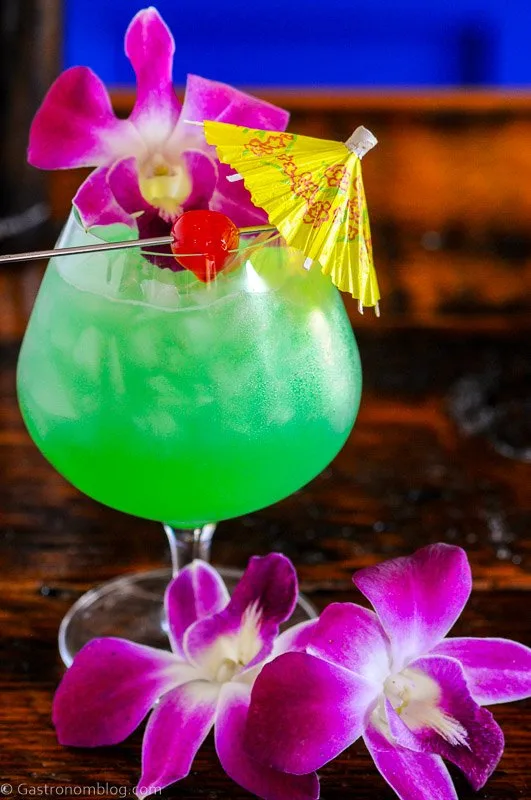 Blue Hawaii cocktail recipe in balloon glass with orchids, paper umbrella and cherry