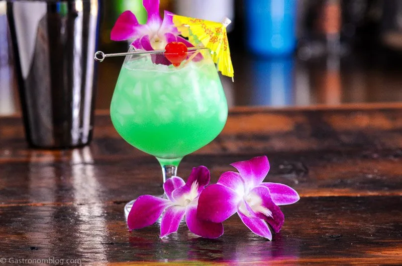 Blue Hawaii cocktail recipe in balloon glass with orchids, paper umbrella and cherry