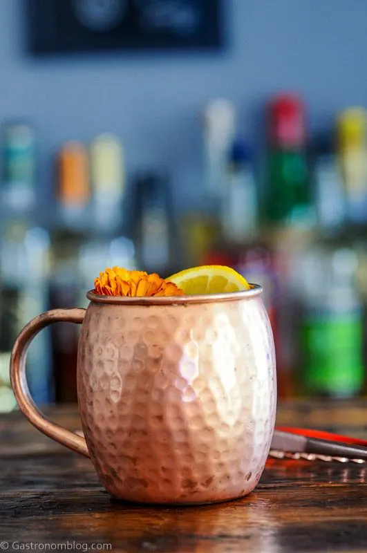 Orange Moscow Mule in a copper mug with an orange slice and orange flower