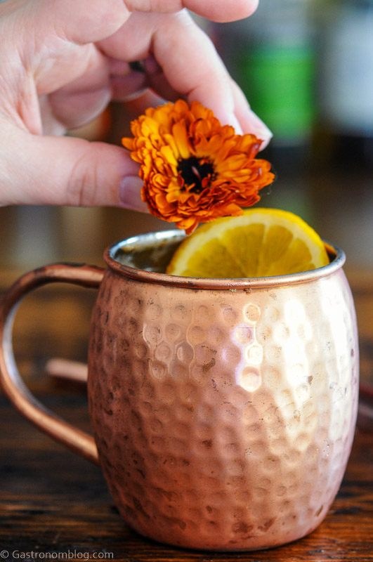 Orange Moscow Mule in a copper mug with an orange slice and orange flower