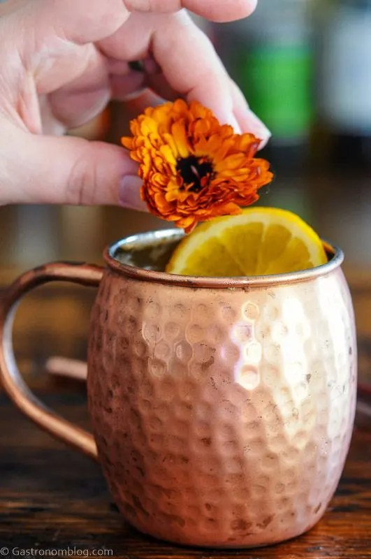 Orange Moscow Mule in a copper mug with an orange slice and orange flower