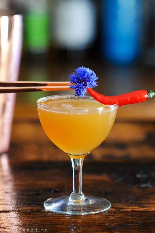 Hot Honey Cocktail in coupe with chili pepper and edible flower