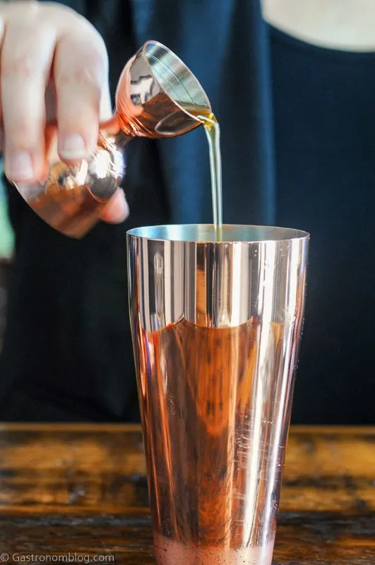 Pouring gold cocktail from bronze shaker