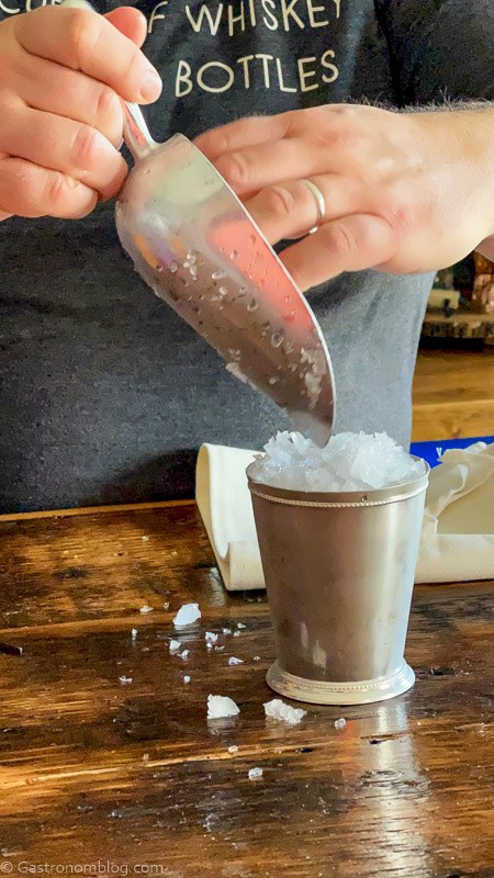 Pouring ice from an ice scoop into a silver cup