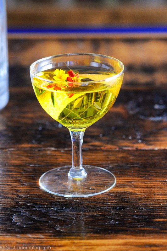 White Negroni in a coupe with edible flowers