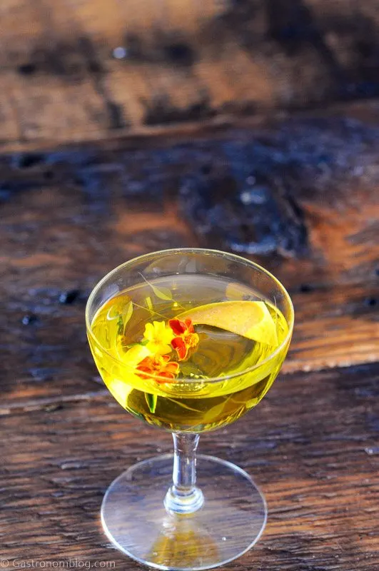 Yellow cocktail in coupe with edible flowers