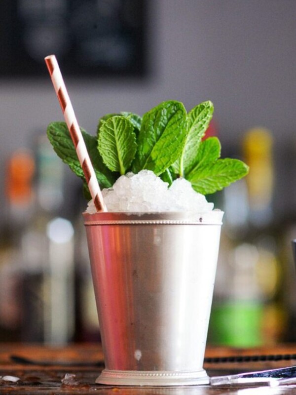 mint julep in a silver julep cup with mint and a straw