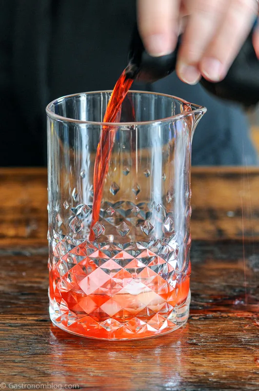 Campari being poured into mixing glass with ice