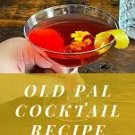 red Old Pal cocktail recipe in coupe with edible flowers and lemon peel