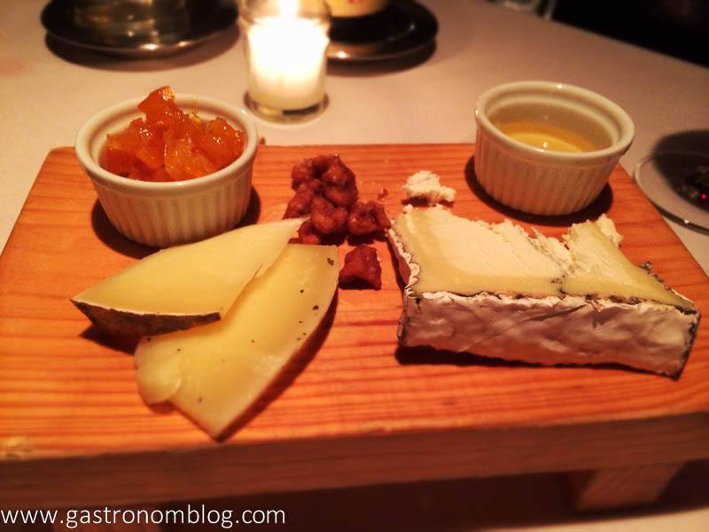 Cheese plate with cheeses on wood board, jam and honey in white ramekins