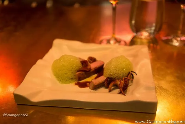 Pork with squid, green foam on white plate at e by Jose Andres
