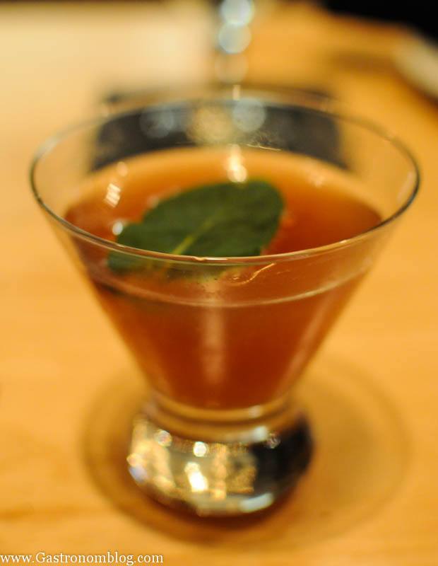 Brown cocktail in glass garnsihed with a green leaf