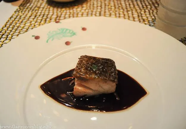 Sea Bass with brown sauce on white plate