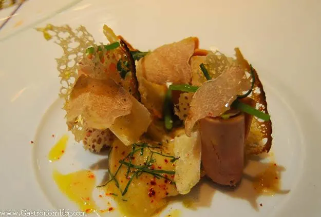 Shaved foie gras and potatoes with garlic shoots and mustard sauce on white plate