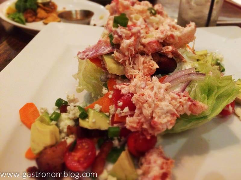 Lobster meat on top of wedge salad on white plate