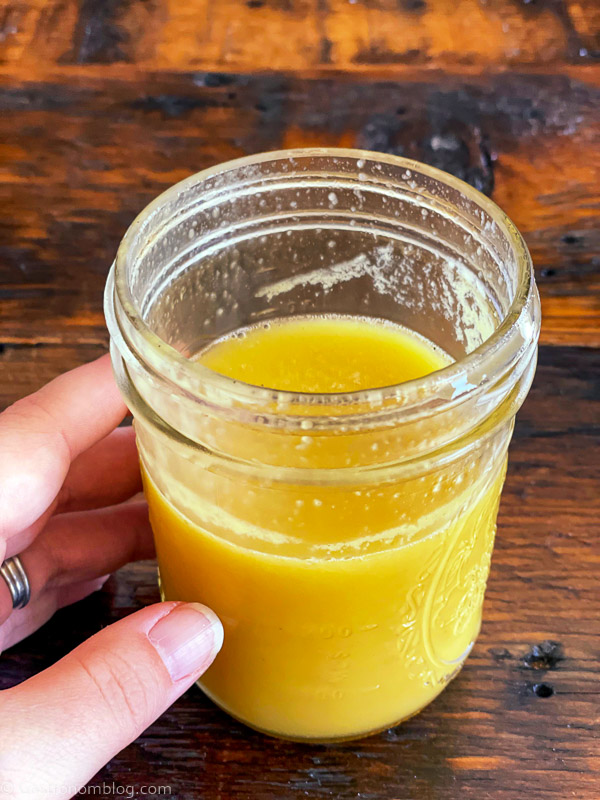 Yellow juice in a jar, hand holding jar
