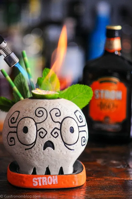 Skull mug with fire from lime slice, Stroh Rum bottle behind