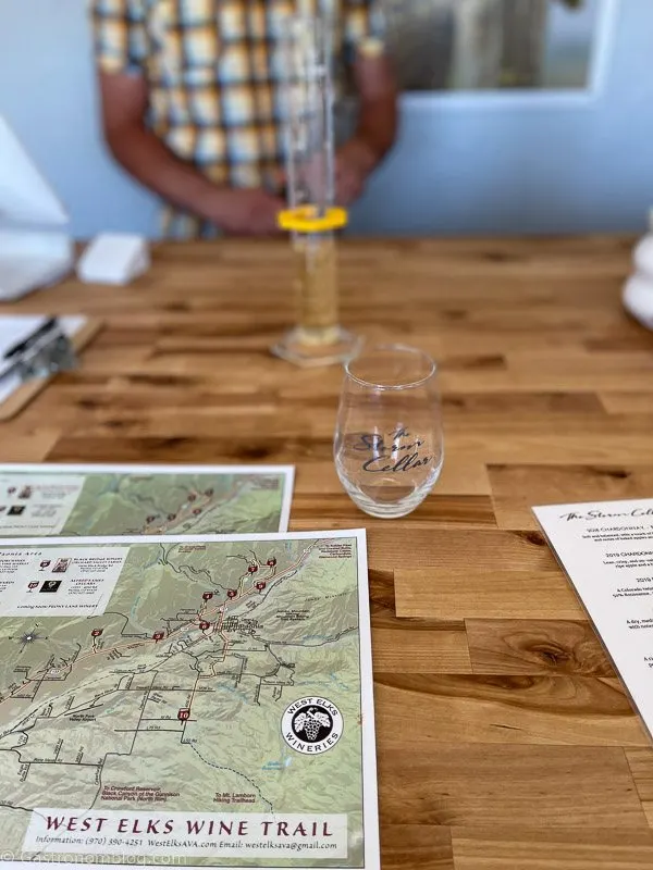 wine in glass and test tube on wooden counter with maps