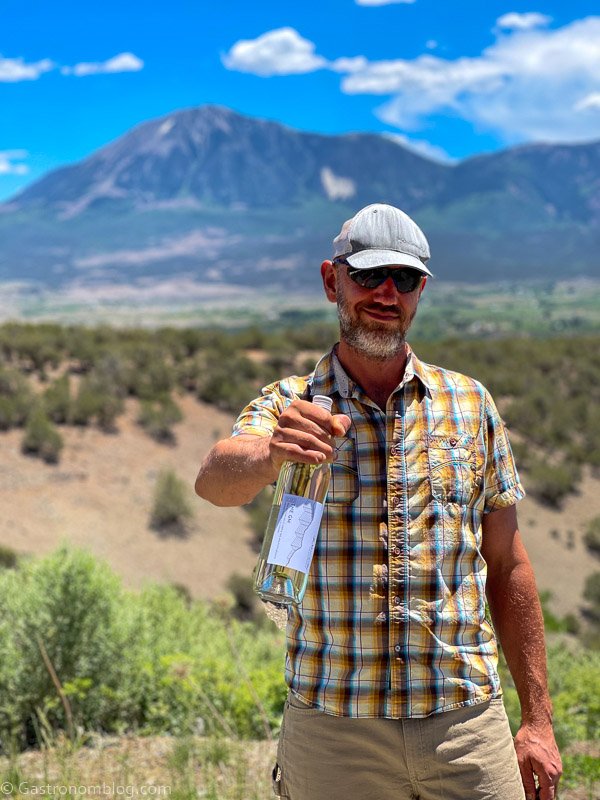 Steve Steese holding white wine bottle in front of mountains