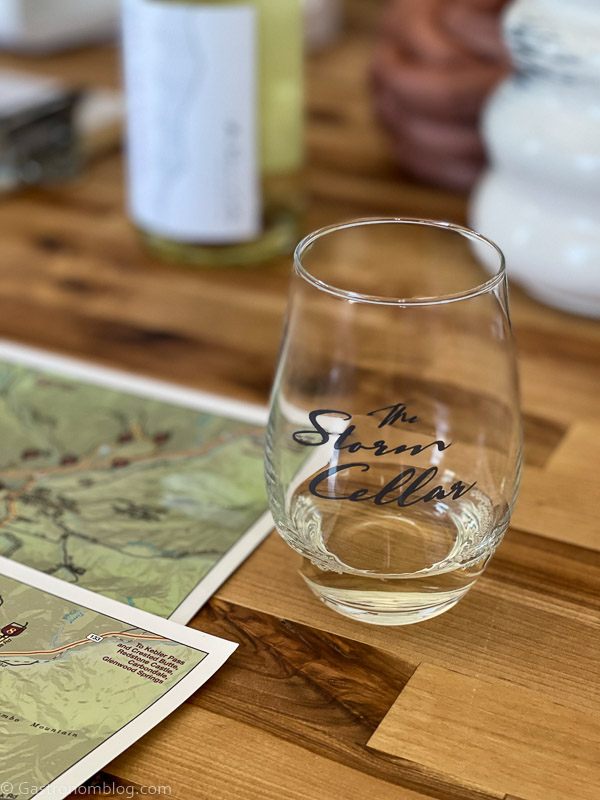 Glass of white wine tasting on a wooden counter. Glass labeled with The Storm Cellar