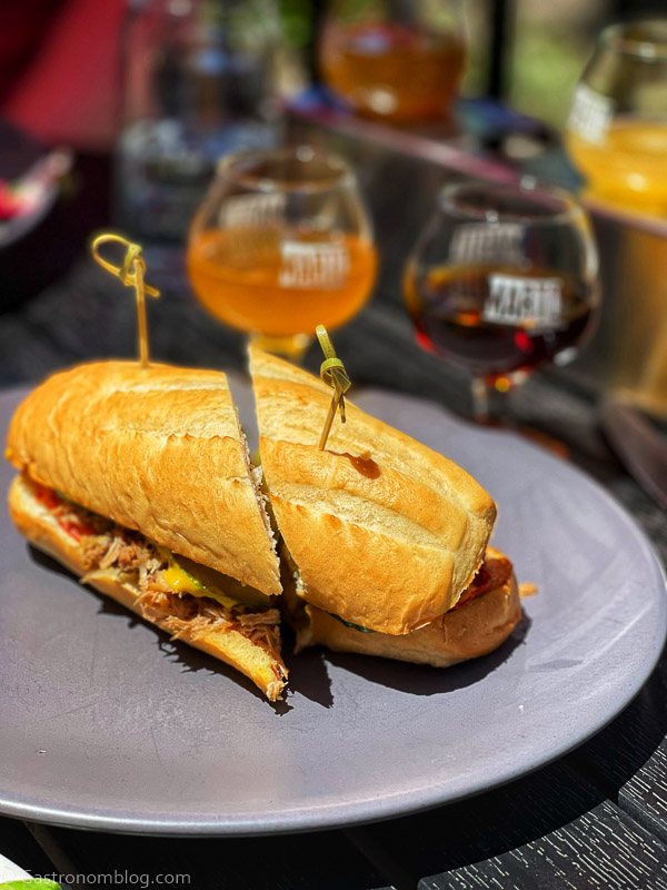 Sandwich on gray plate, beer glasses behind