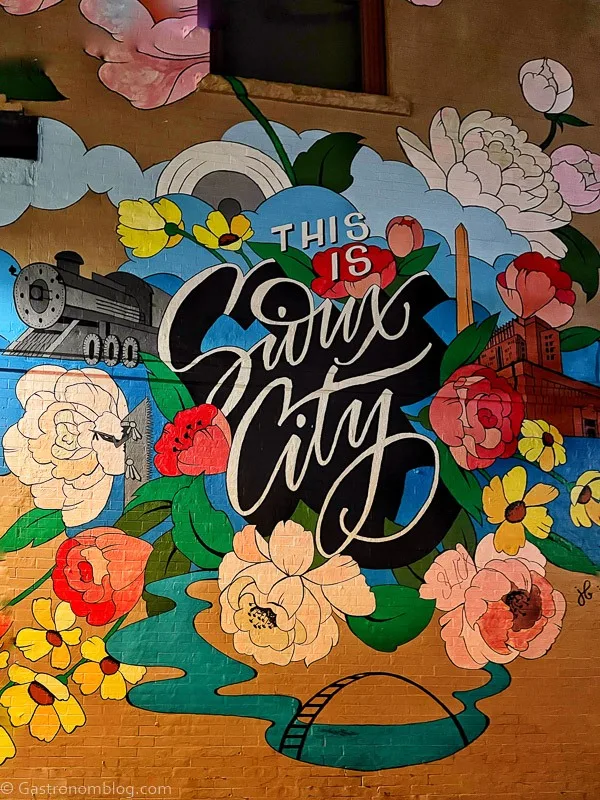 Mural of Sioux City with flowers and cursive writing saying Sioux City for the Iowa Brewery Tour