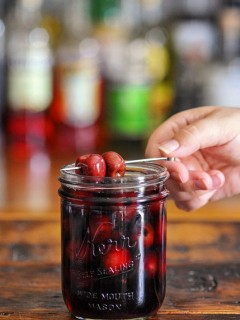 Bourbon cherries on cocktail pick and in jar with red liquid