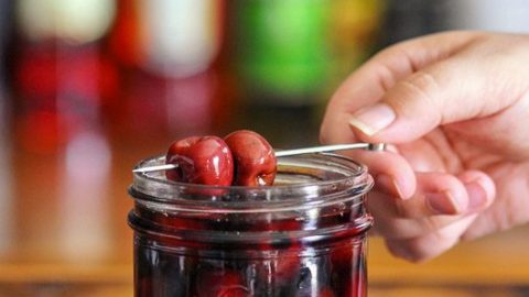 Bourbon cherries on cocktail pick and in jar with red liquid